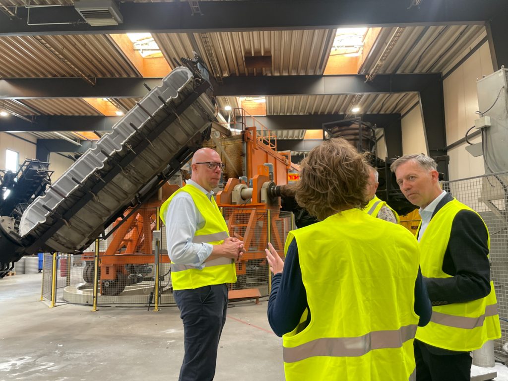 tre personer i reflexvästar i fabrik.